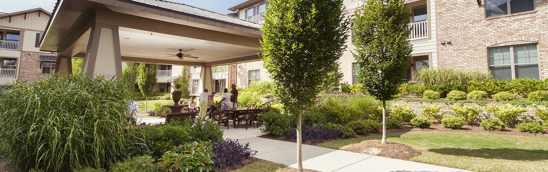 A patio with a table and chairs is surrounded by greenery.